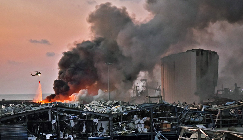 EDITORS NOTE: Graphic content / A helicopter puts out a fire at the scene of an explosion at the port of Lebanon's capital Beirut on August 4, 2020. (Photo by STR / AFP)