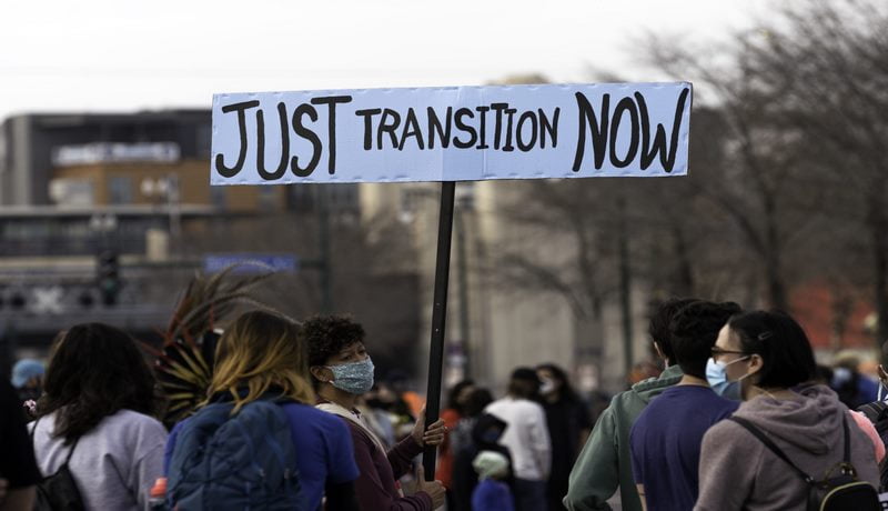 A woman holds a Just Transition Now sign at a rally in Minneapolis Minnesota 50577736571 scaled Copy